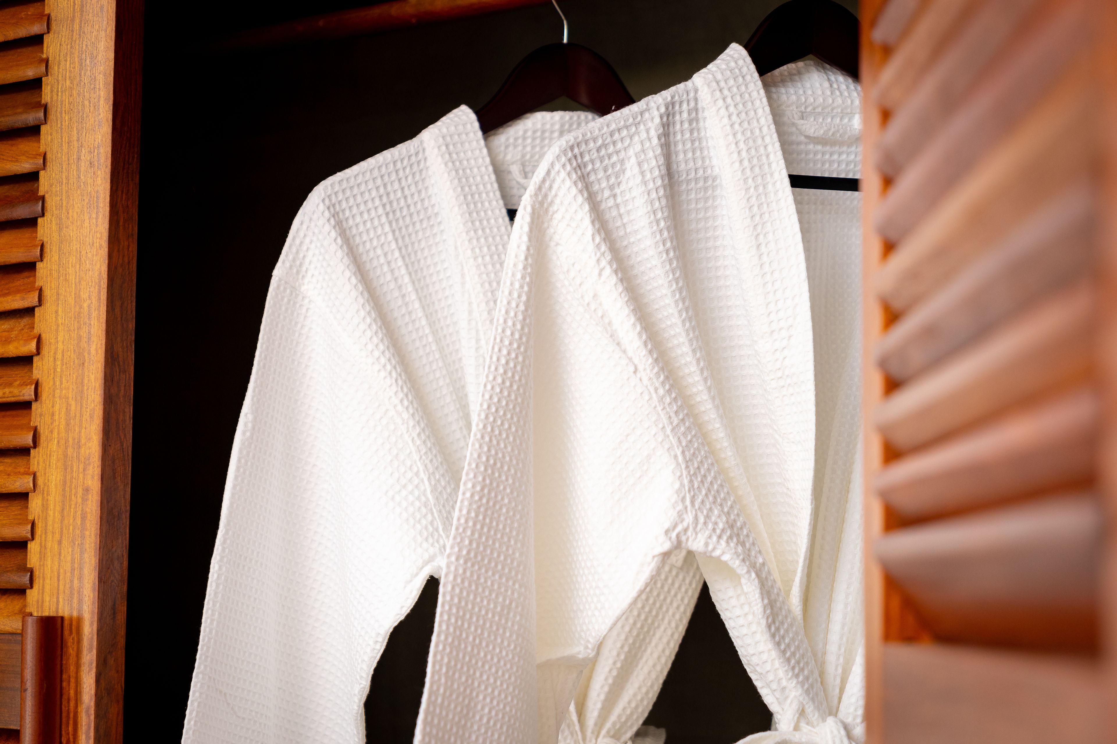 Une robe blanche est suspendue à un cintre en bois dans un placard.