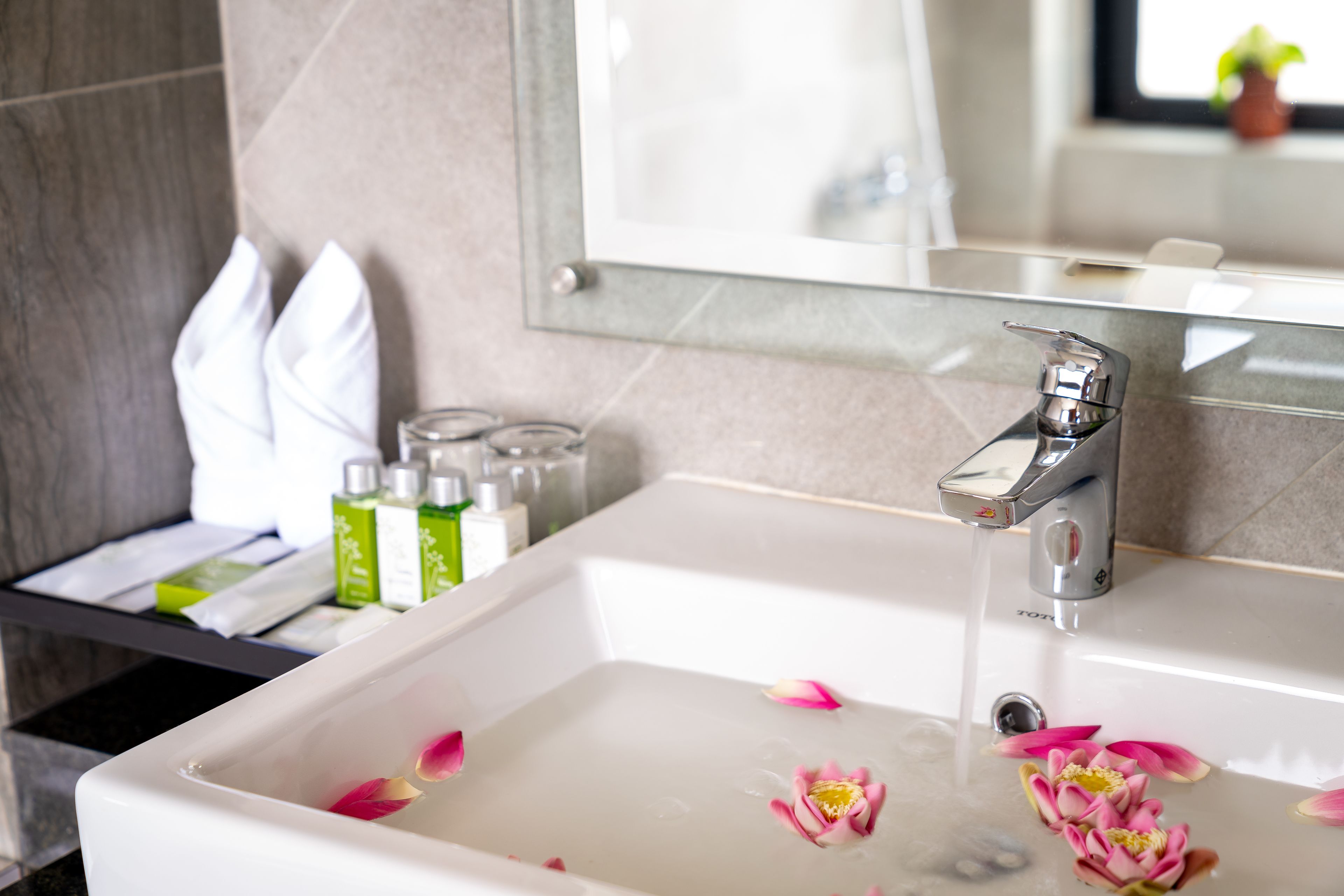 Une salle de bain avec un lavabo blanc, un miroir et des articles de toilette rangés sur une étagère.