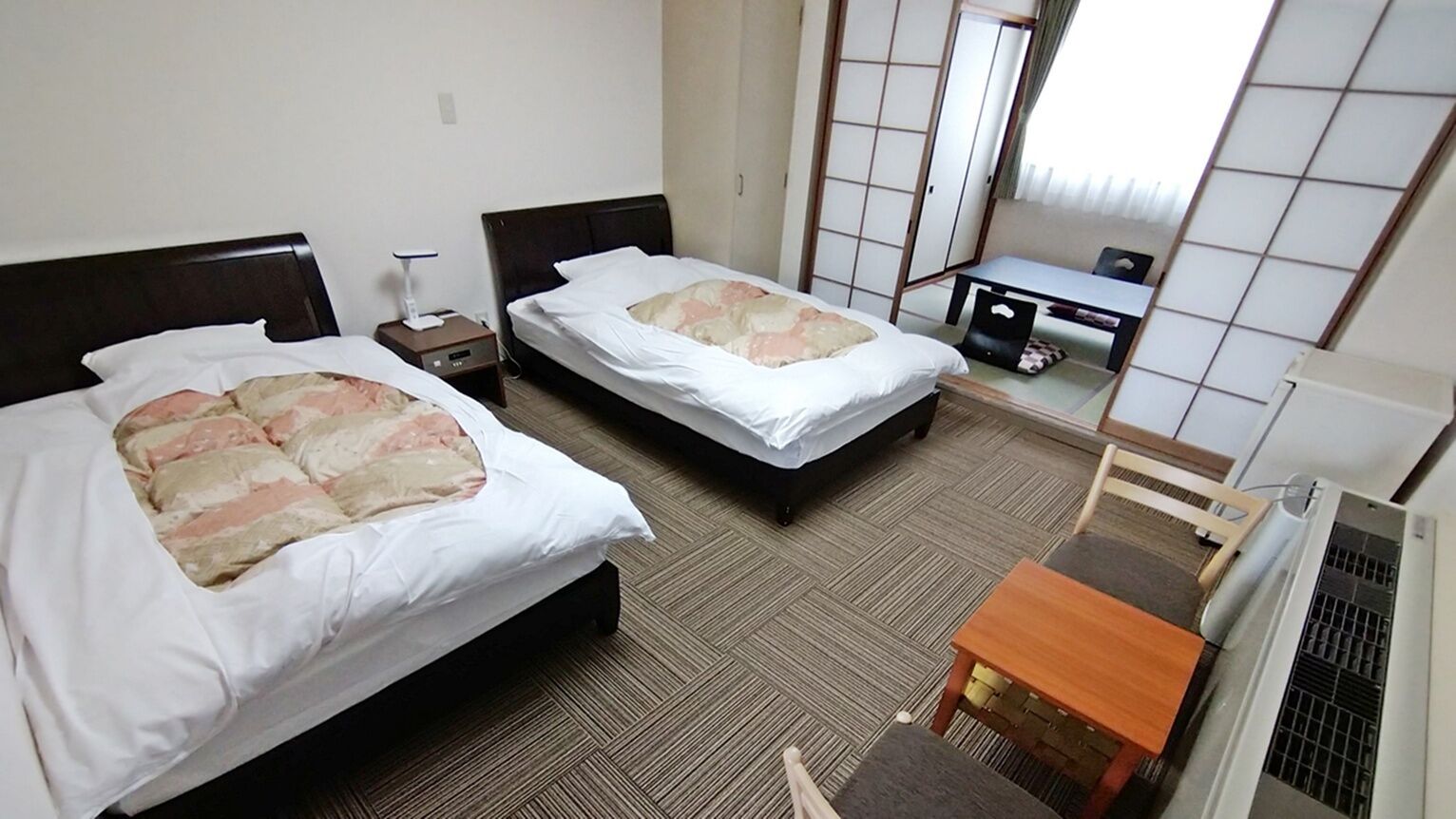 Une chambre d’hôtel avec deux lits, un bureau et une chaise.