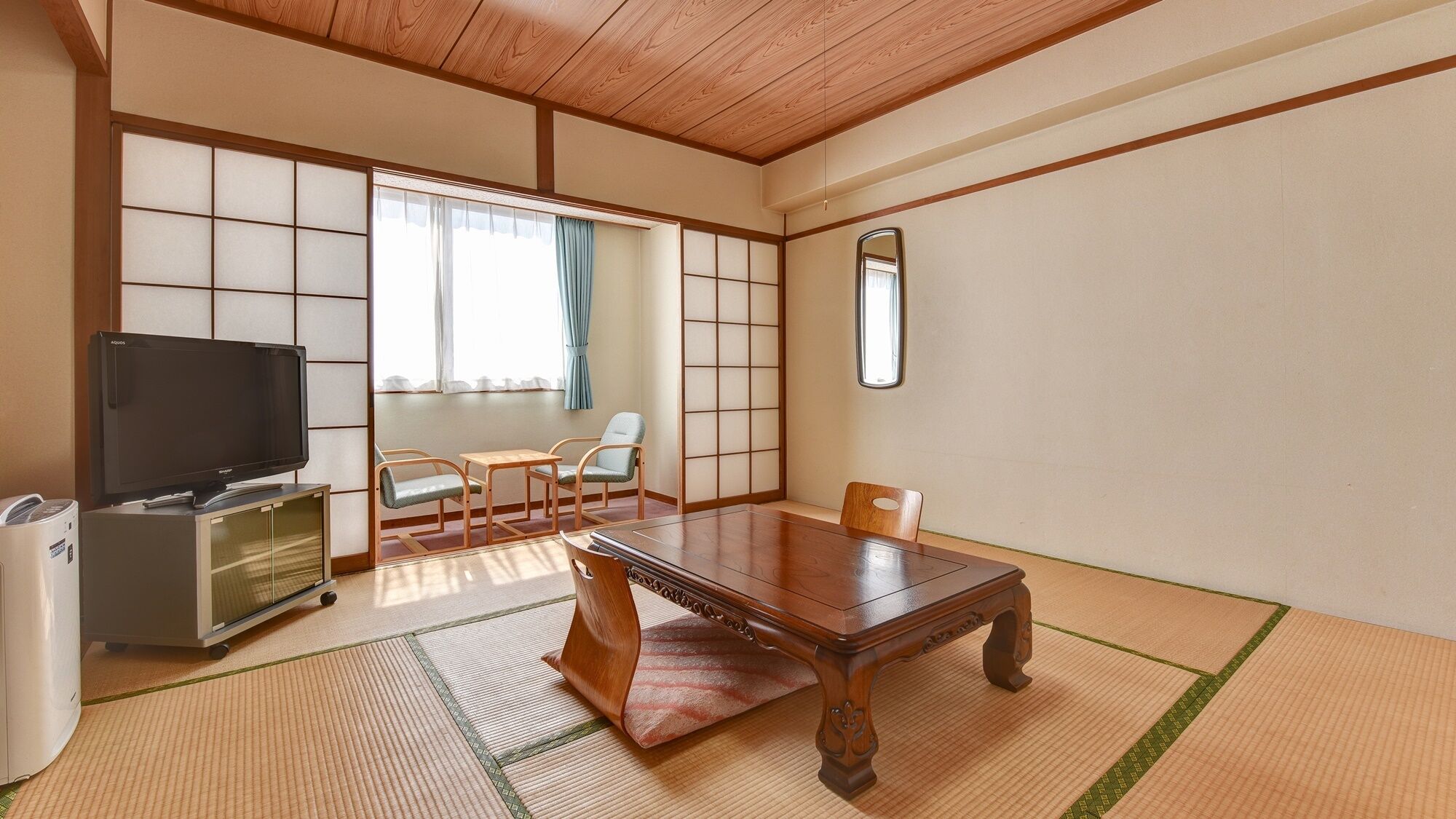 Une pièce de style japonais traditionnel, avec un sol recouvert de tatamis, une table en bois, un téléviseur et une porte coulissante.