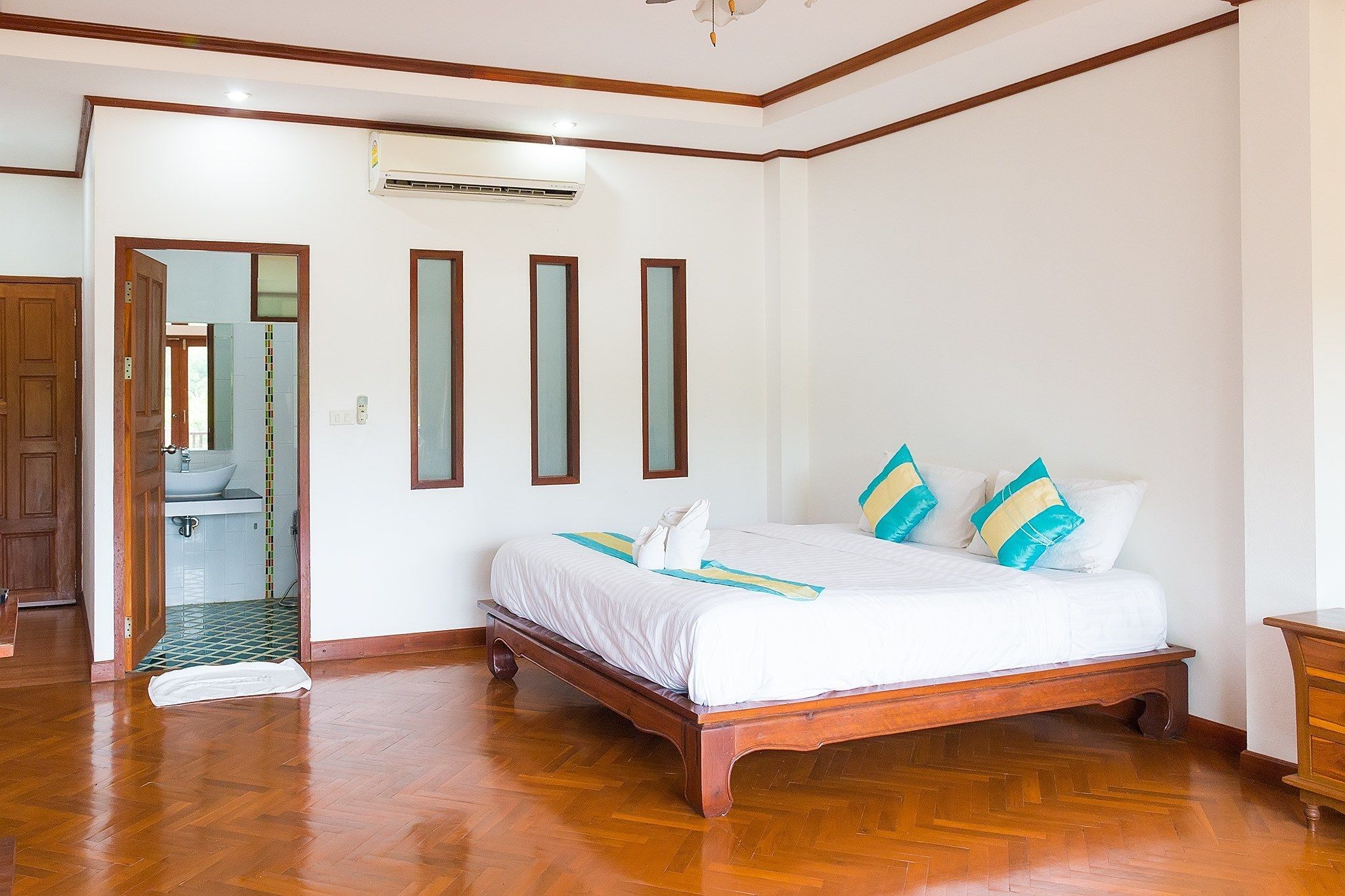 A bedroom with a wooden bed, white bedding, and a bathroom visible through an open door.