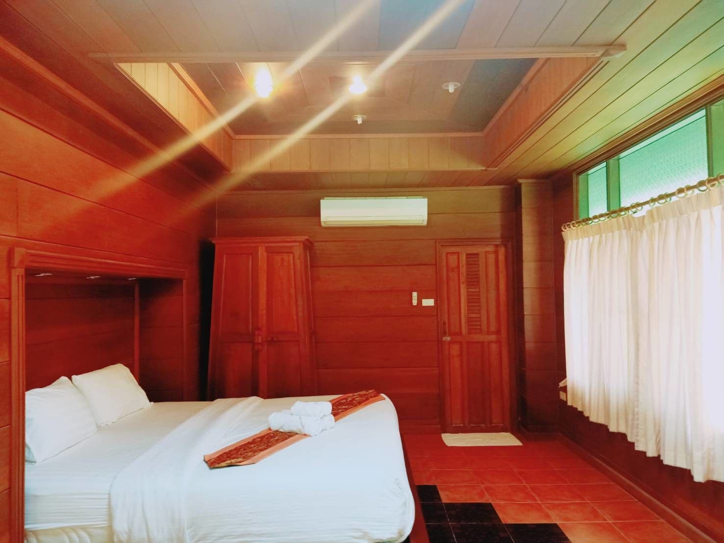 Habitació d'hotel amb llit, armari de fusta i finestra amb cortines.