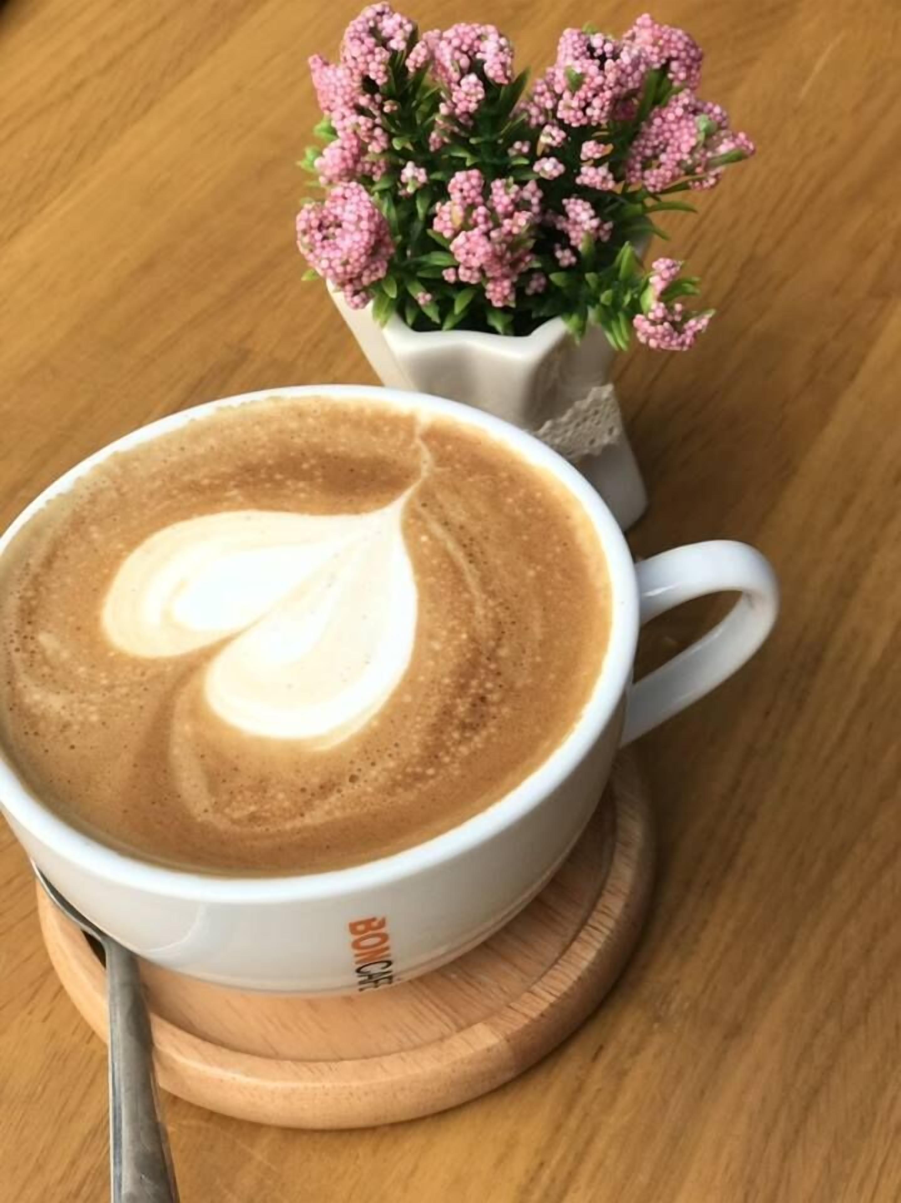 A cup of coffee with latte art on a wooden coaster.
