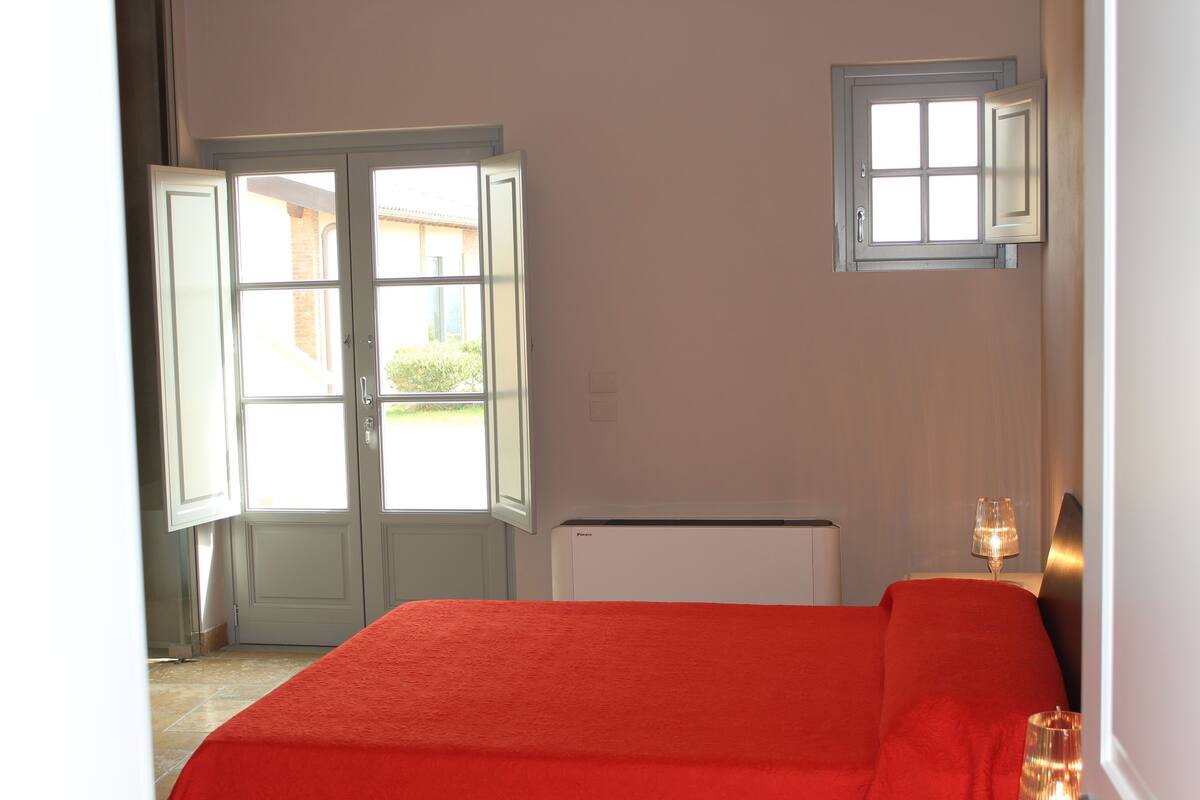 A room with a bed, a radiator, a window, and a door.