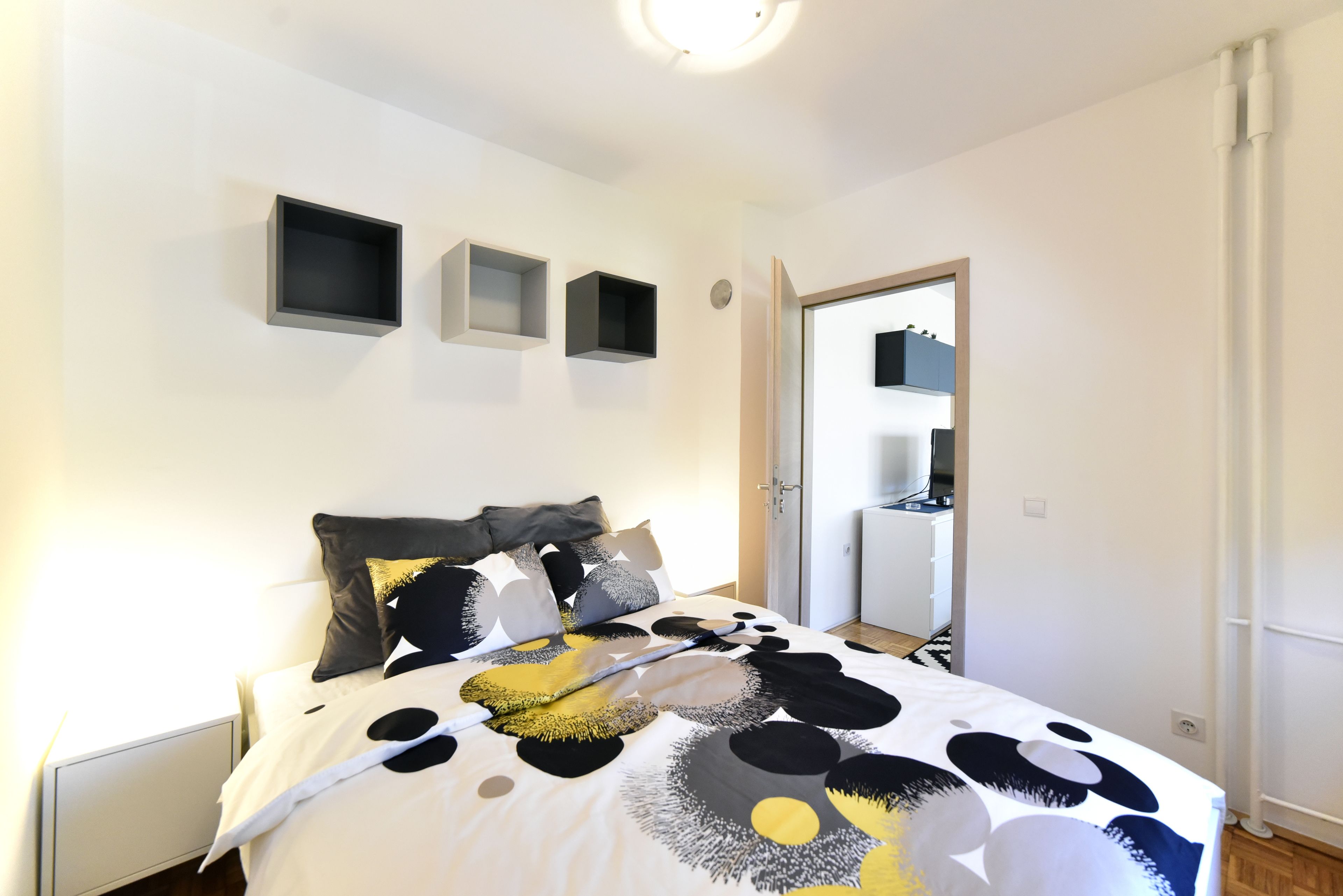 A bedroom with a bed, bedside tables, a wardrobe, and a mirror.