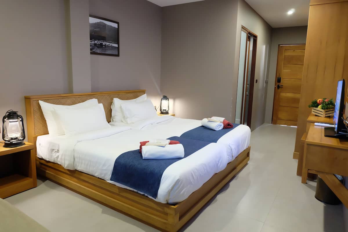 A neatly made bed with white and blue bedding, a bedside table with a lantern, and a wooden nightstand.