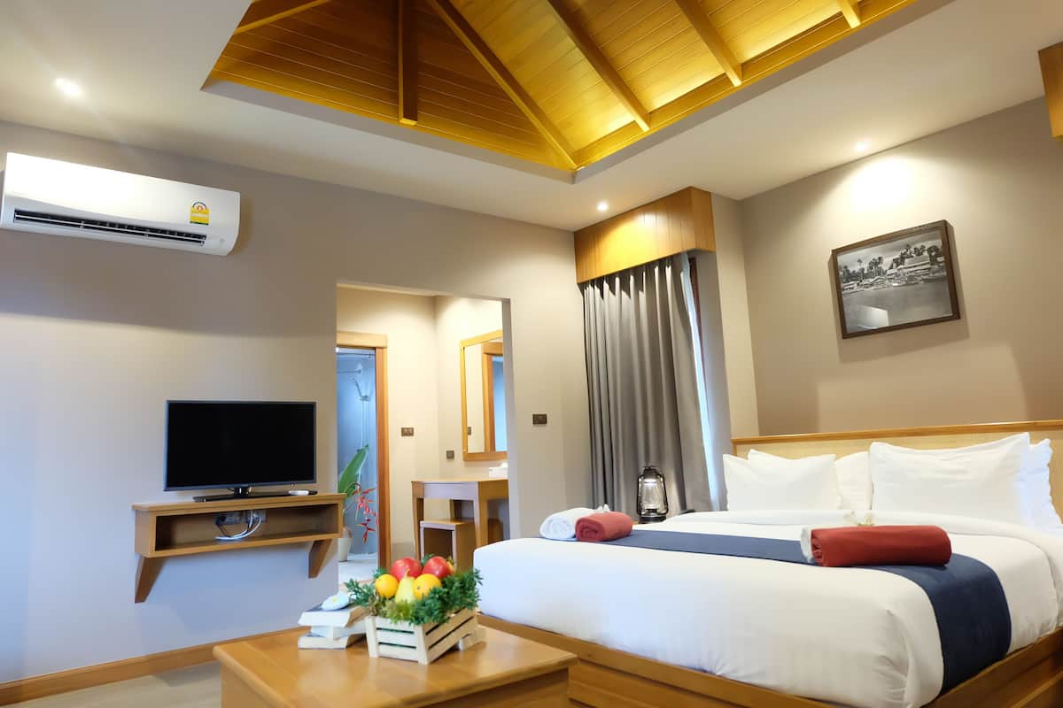 A modern hotel room with a bed, TV, bedside table, and a wall-mounted air conditioner.