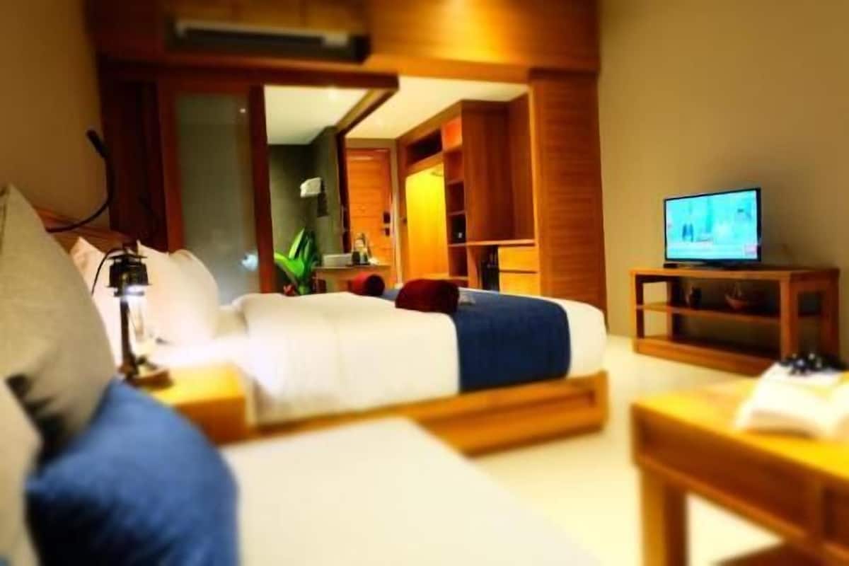 A hotel room with a bed, a TV, and a wooden side table.