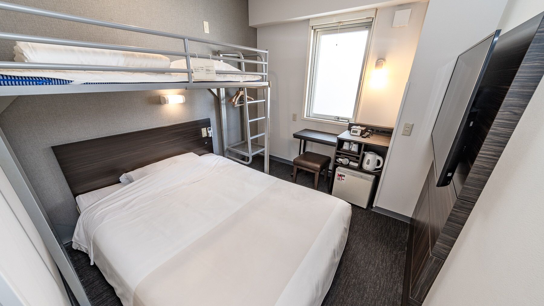 A bunk bed with a desk and a small kitchenette.