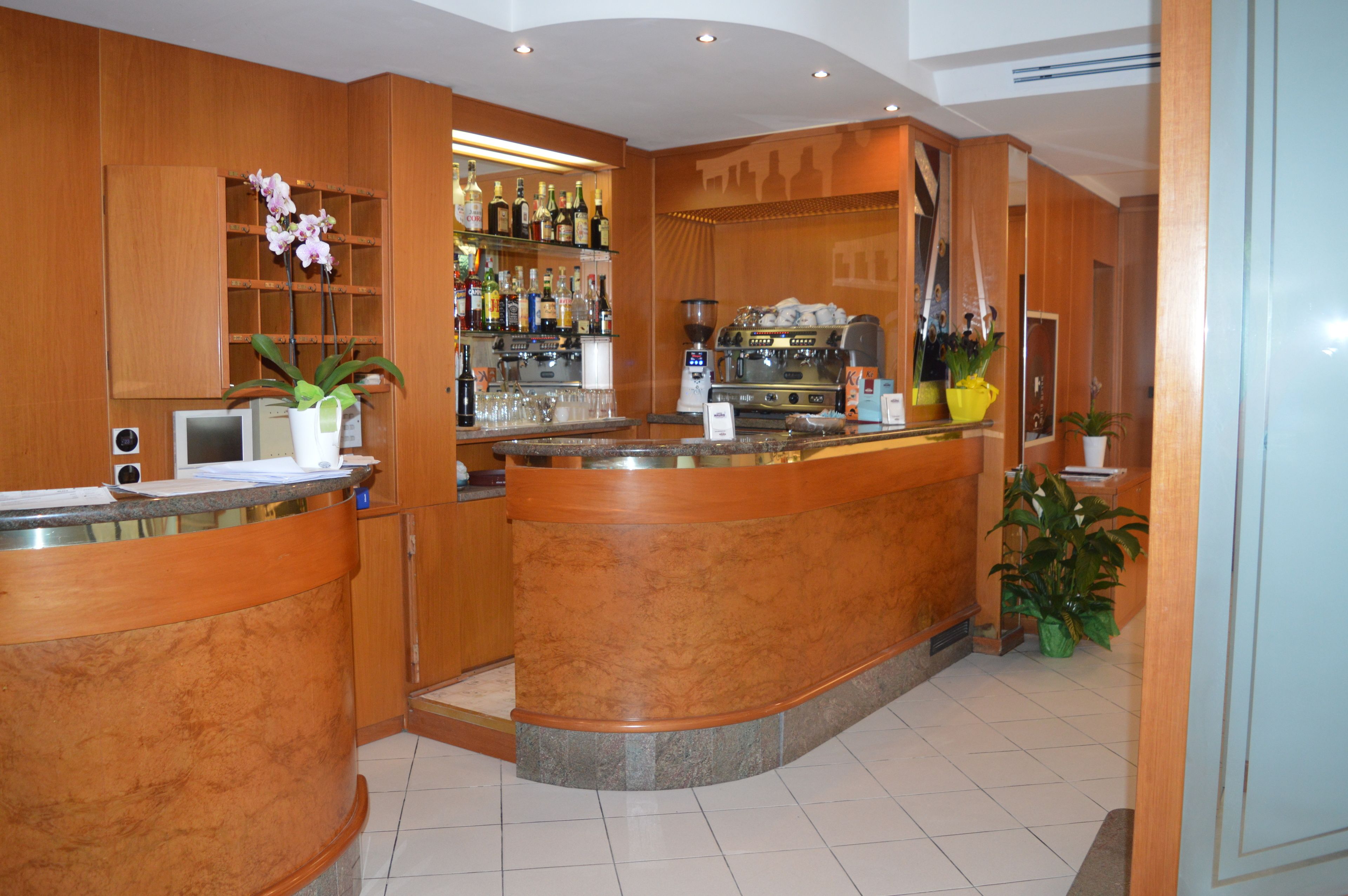 A bar area with wooden cabinets, a countertop, and a coffee machine.