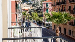 Varanda com vista para uma rua ladeada por edifícios, incluindo uma igreja com duas cúpulas.