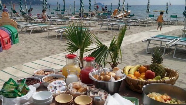 Café da manhã à beira-mar com diversas opções de comida e vista para a praia e oceano.