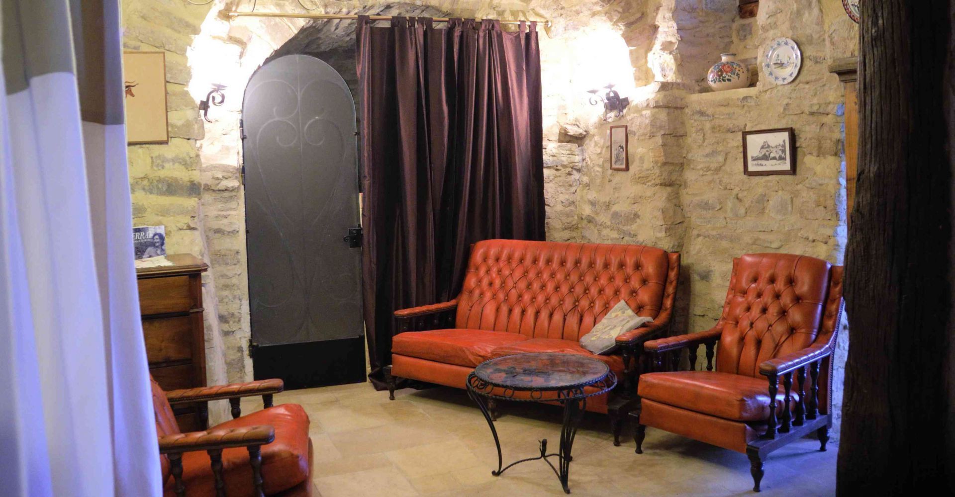 Una habitación con pared de piedra, un gran ventanal y dos sillones de cuero con una pequeña mesa redonda.