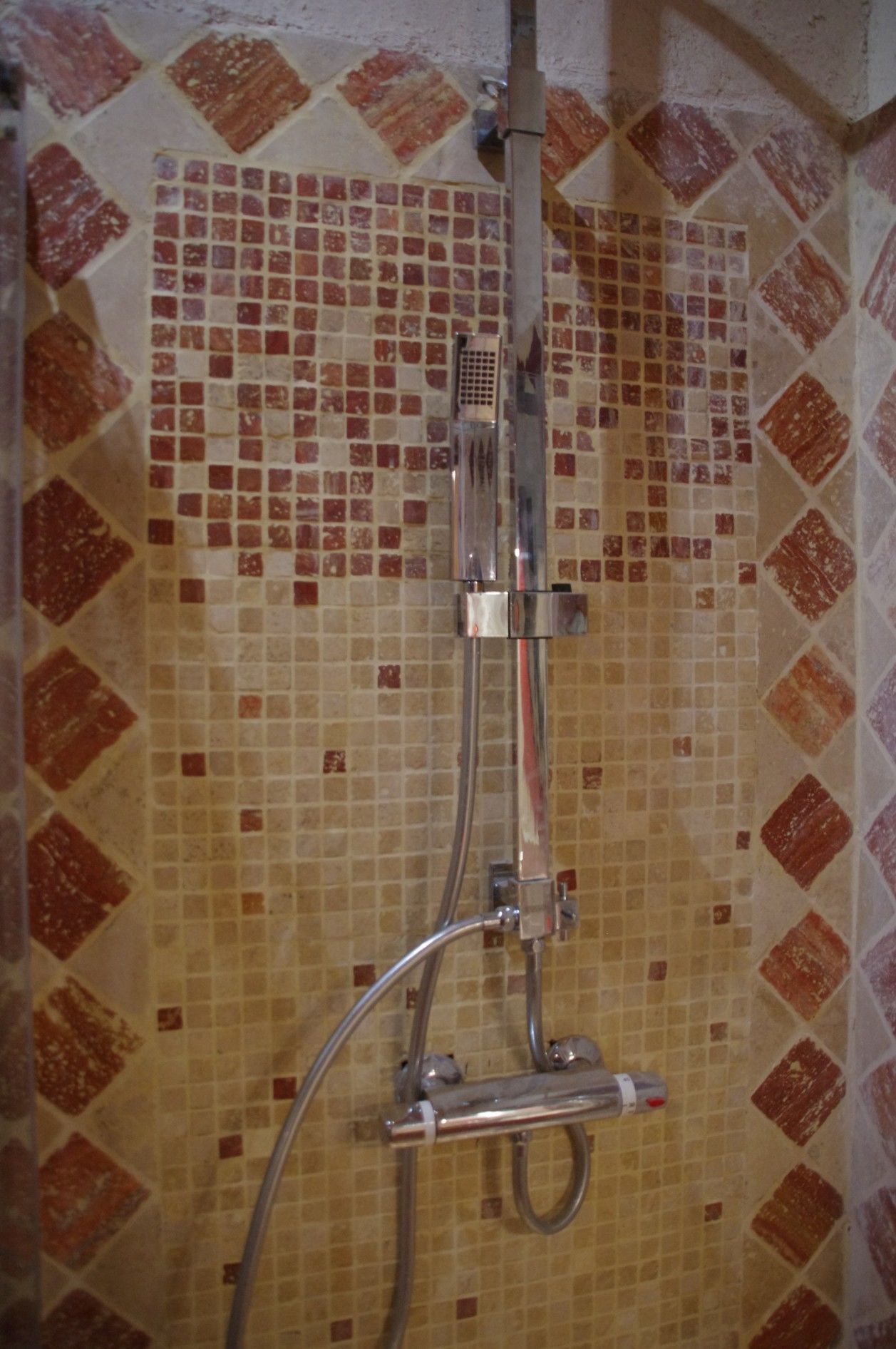 Eine Dusche mit gefliesten Wänden und einem chromfarbenen Duschkopf.