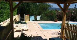 Un espace piscine avec des chaises longues et une pergola.