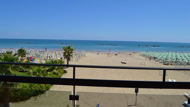 A beach with umbrellas and lounge chairs, a clear sky, and the ocean. - Hotel Quaglia (Roseto degli Abruzzi)
