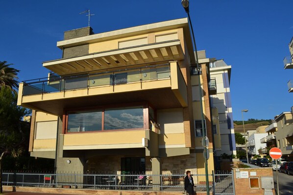 A multi-story building with a flat roof, large windows, and a balcony.