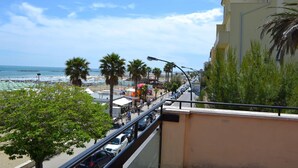 A coastal street with a beach in the background, palm trees, and a building with balconies. - Hotel Quaglia (Roseto degli Abruzzi)