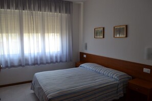 A bedroom with a bed, a nightstand, a wooden headboard, and two framed pictures on the wall.