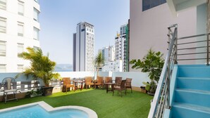A rooftop pool area with a blue staircase, outdoor seating, and a view of surrounding buildings. - Sunshine Hotel Nha Trang (Nha Trang)