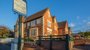 A traditional brick building with a sign for 'Thick Bacc & Railway Hotel'. - The Beacon Inn (Stonehouse)