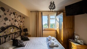 A neatly made bed with white linens and decorative pillows, a bedside table with a lamp, and a wooden nightstand with a coffee maker. - The Beacon Inn (Stonehouse)