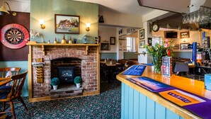 A pub with a dartboard, a fireplace, and a bar area with a menu. - The Beacon Inn (Stonehouse)