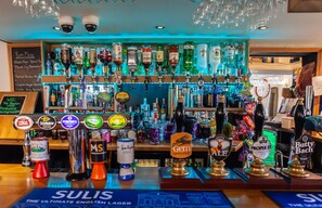 A bar area with multiple liquor bottles and a variety of beer taps.