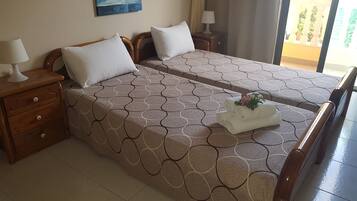 Une chambre d’hôtel avec deux lits, chacun recouvert d’une couvre-lit à motifs, une table de chevet avec une lampe et un tableau accroché au mur.