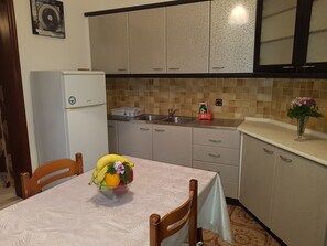 Eine Küche mit Kühlschrank, Spüle und einem Tisch mit Obstschale.
