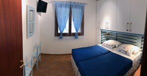 A bedroom with a bed, a window with curtains, a TV, and a wardrobe. - RELAX, SUN & SEA ... everything away from home !!! (Olbia)