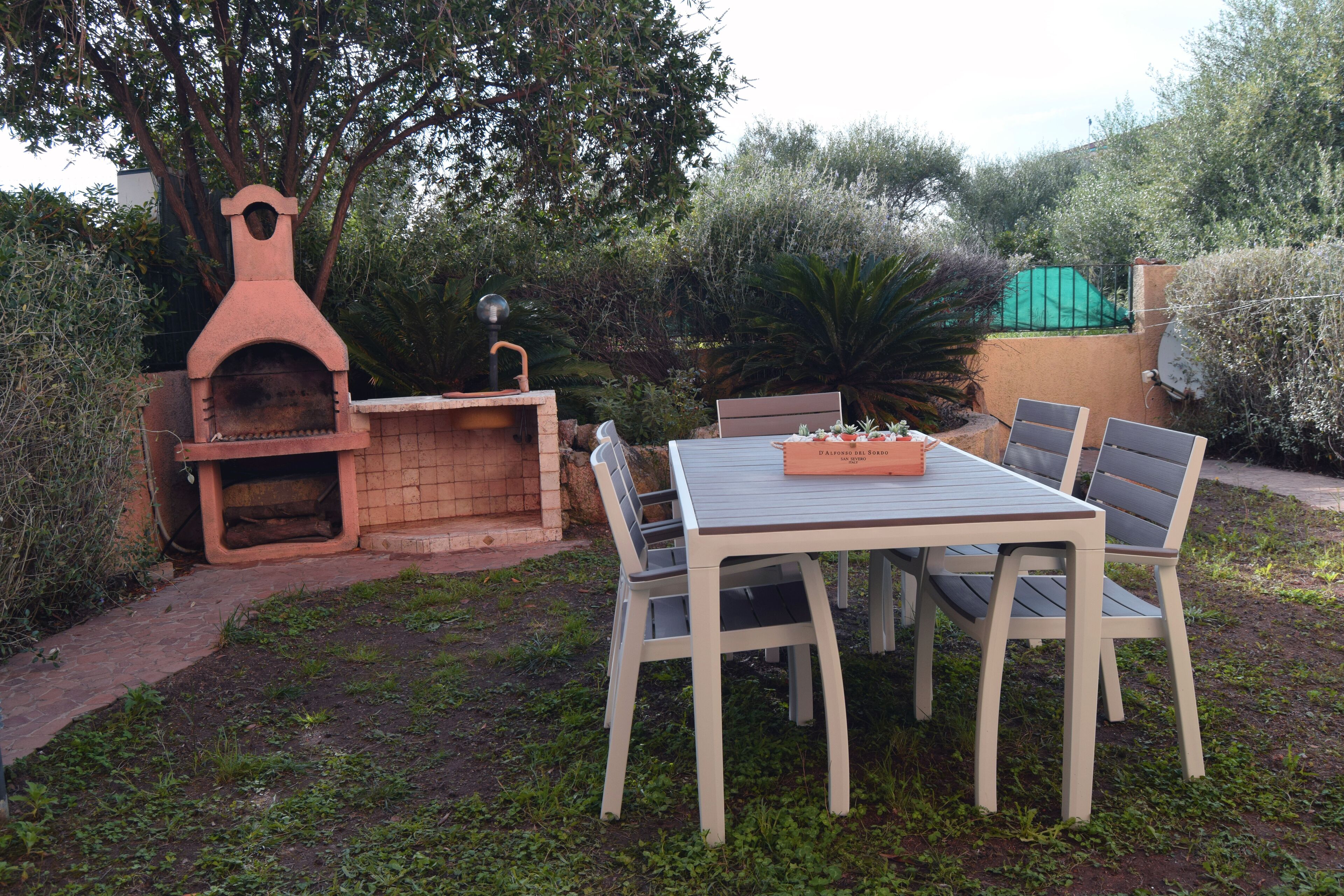 Un patio al aire libre con un horno de ladrillo, una mesa y sillas.