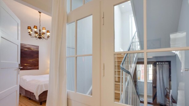 A bedroom with a bed, a chandelier, and a view of a staircase. - The locksmith's shop awarded 5 stars according to DTV (Westerland)