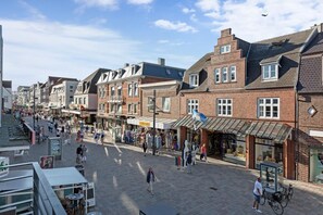 A pedestrian street lined with brick buildings, shops, and outdoor seating areas. - The locksmith's shop awarded 5 stars according to DTV (Westerland)