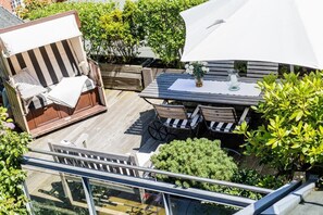 An outdoor deck with a wooden table, chairs, and a cushioned seating area. - The locksmith's shop awarded 5 stars according to DTV (Westerland)