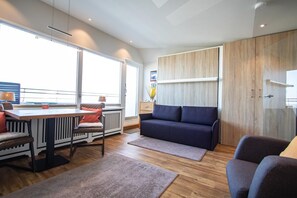 Una sala de estar moderna con sofá, mesa de comedor y un ventanal grande.