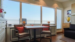 A modern kitchen with a large window, two chairs, a table, and a black sofa. - Metro 335 - with stunning views over the island (Westerland)