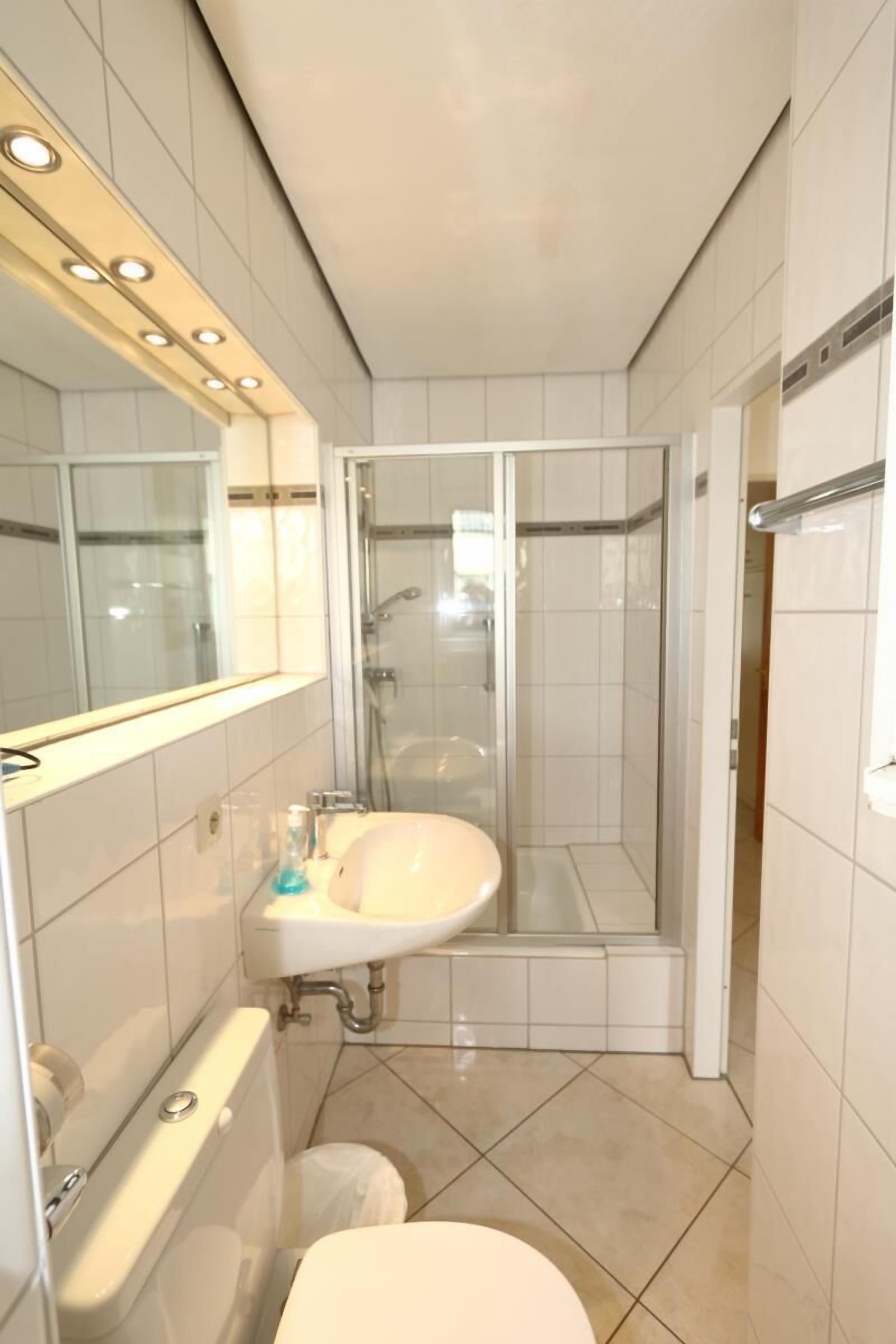 A modern bathroom with a toilet, sink, and shower.