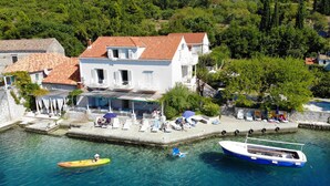 A coastal town with a dock, boats, and a building with a red-tiled roof. - Apartment Cecilija - waterfront with sunbeds (Zaton)