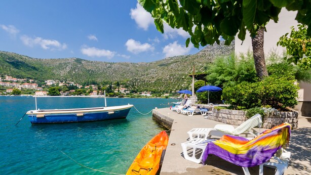 A boat docked at a pier with a clear view of the sea and a mountainous landscape in the background. - Apartment Cecilija - waterfront with sunbeds (Zaton)
