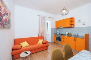 A compact living space with a sofa, dining table, and kitchen area.