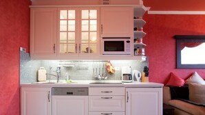 Uma cozinha com armários brancos, micro-ondas, cafeteira e pia.
