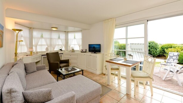 Een woonkamer met een bank, een salontafel, een televisie en een eethoek met een tafel en stoelen.