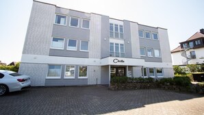 Il s’agit d’un bâtiment moderne sur lequel on peut lire l’inscription « Cacilia ». Il se distingue par sa façade en briques, ses nombreuses fenêtres et son entrée pavée.