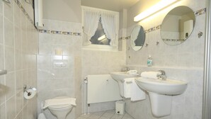 Une salle de bain équipée de toilettes, d’un bidet, d’un lavabo et de miroirs.