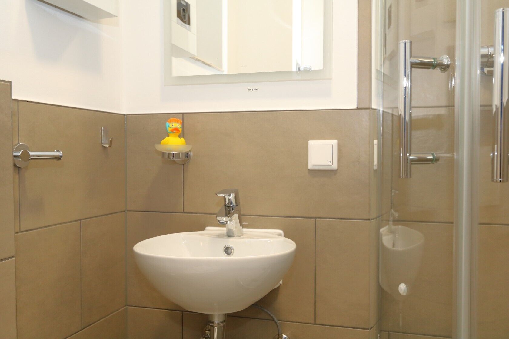 A bathroom with a white sink, chrome faucet, and a glass shower enclosure.