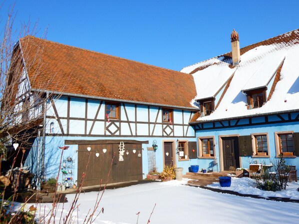 A traditional half-timbered house with a snow-covered roof and a blue facade.