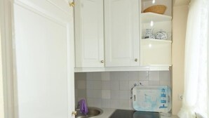 A compact kitchen with white cabinetry, a built-in dishwasher, and a small sink.