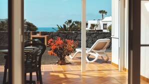 A patio with a chair, a table, and a potted plant. - Apartamentos Livvo Coloradamar (Yaiza)
