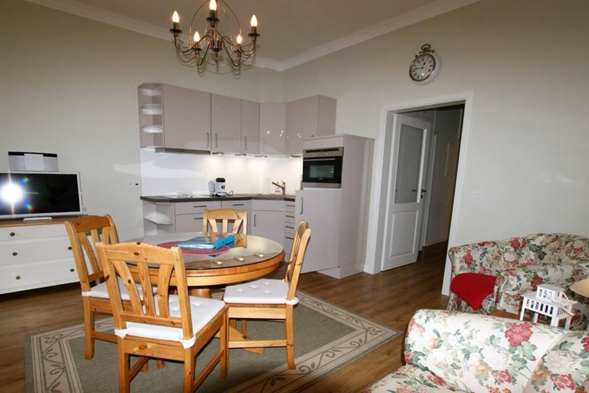 A compact living space with a dining area, kitchenette, and a floral sofa.